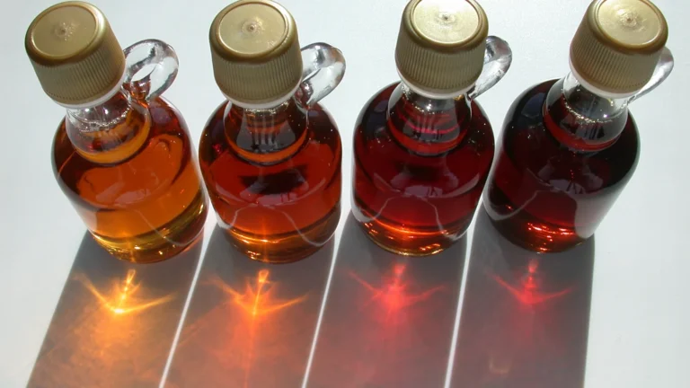 Four glass bottles of maple syrup in different grades, from golden to very dark