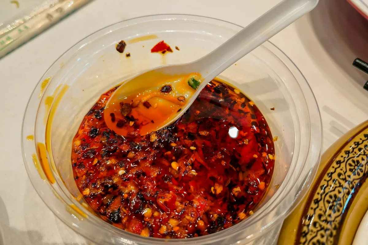 A bowl of red chilli flakes and seeds in oil, the kind of heat used to make hot honey