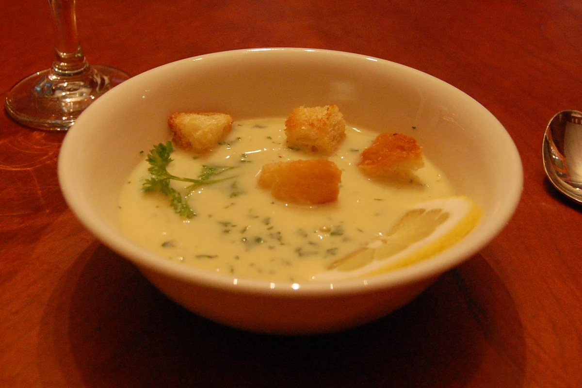 A bowl of pale, creamy egg-lemon soup with herbs