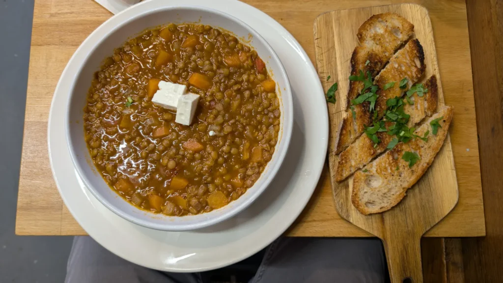 A bowl of fakes, Greek lentil soup with tomato, topped with feta and served with toasted bread