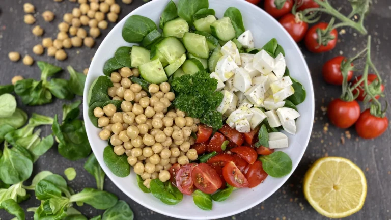 A bowl of chickpea salad with cucumber, cherry tomatoes, white cheese and herbs