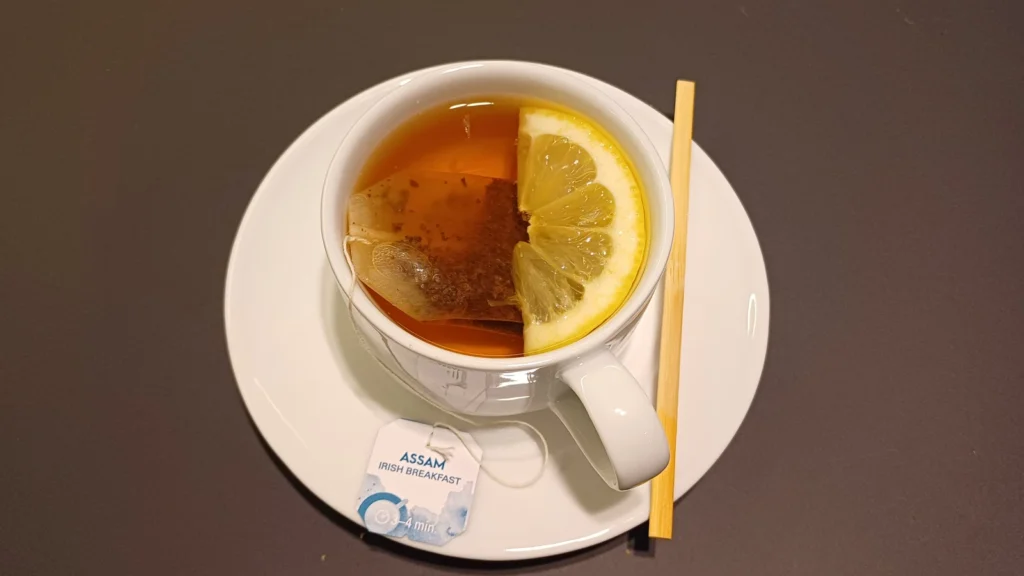 A cup of black tea with a lemon slice on a saucer