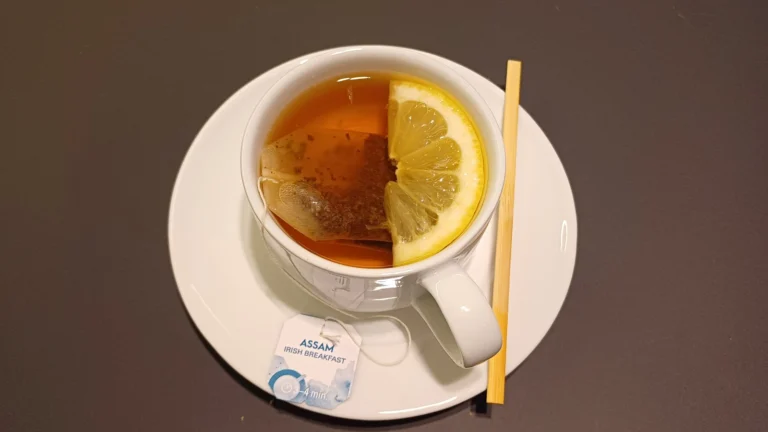 A cup of black tea with a lemon slice on a saucer