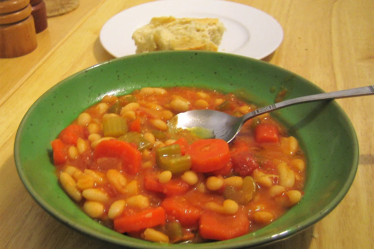 White beans in a tomato broth with carrots, served in a green bowl