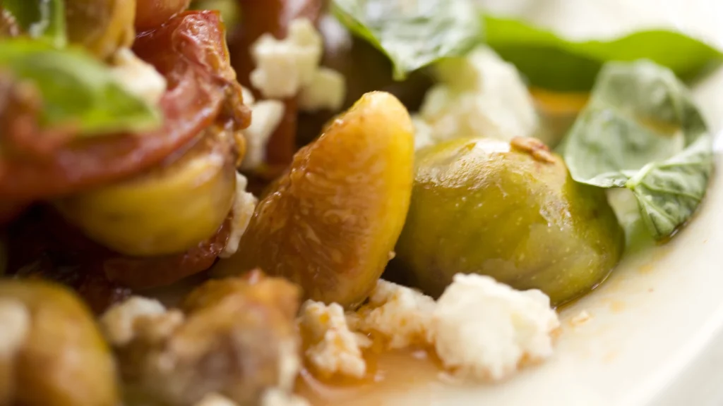 A close-up of a salad of fresh figs with ricotta and basil leaves