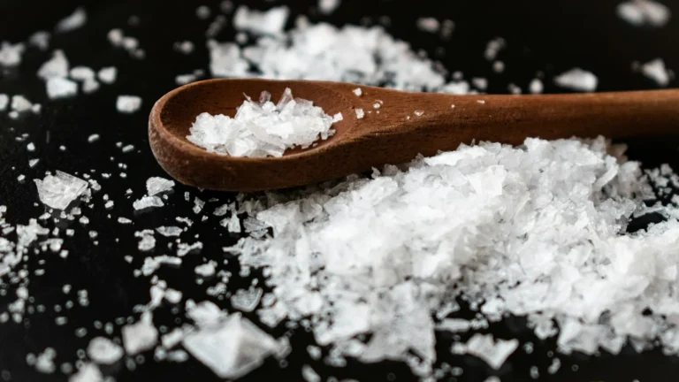 Flaky finishing salt in a wooden spoon, the texture at the heart of fleur de sel vs Maldon