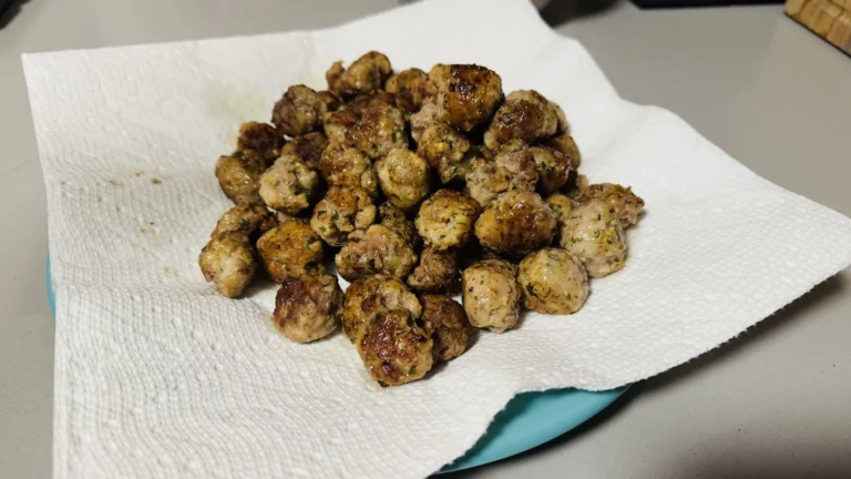 Small browned meatballs draining on paper towels after frying