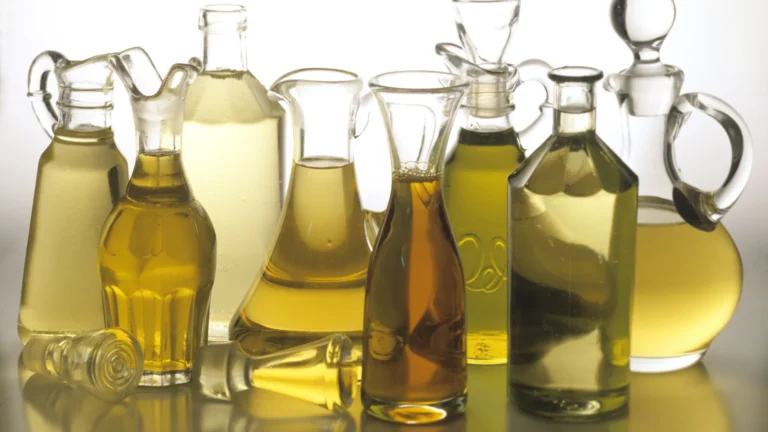 Glass bottles and jugs holding several kinds of cooking oil in shades of gold and green