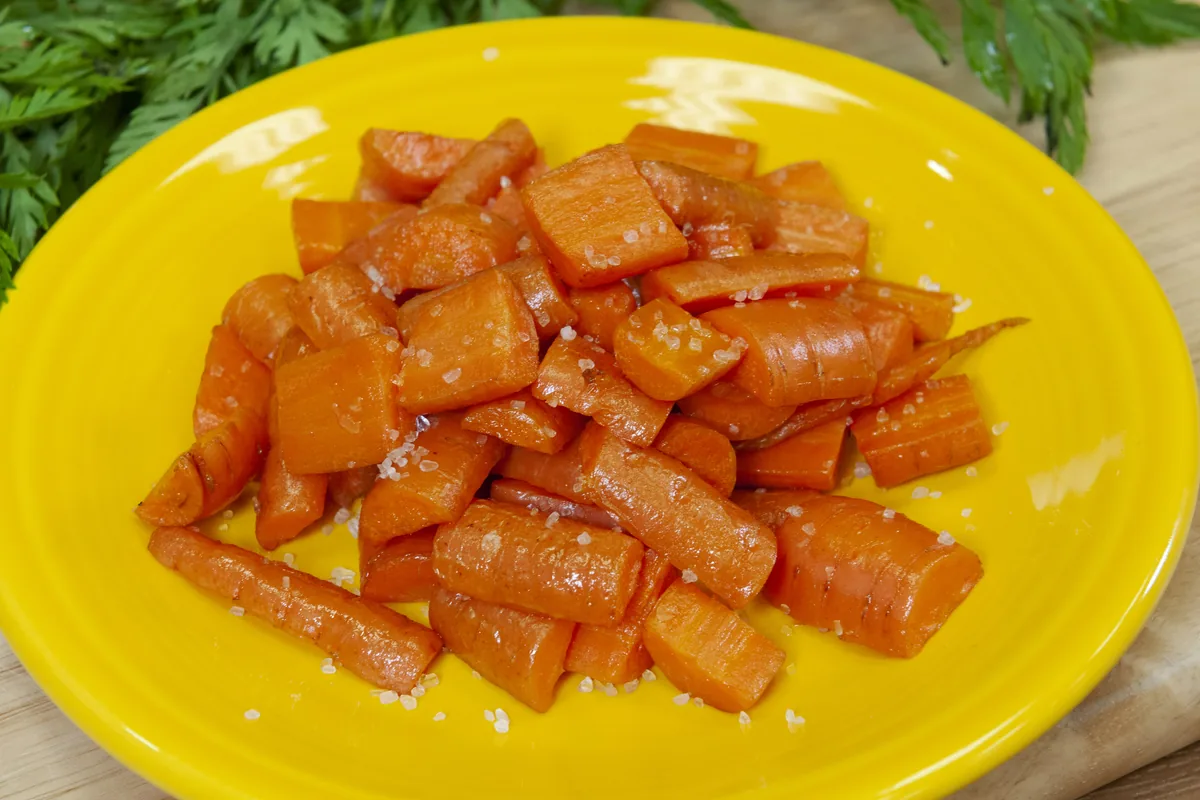 Glossy glazed carrot pieces served on a yellow plate