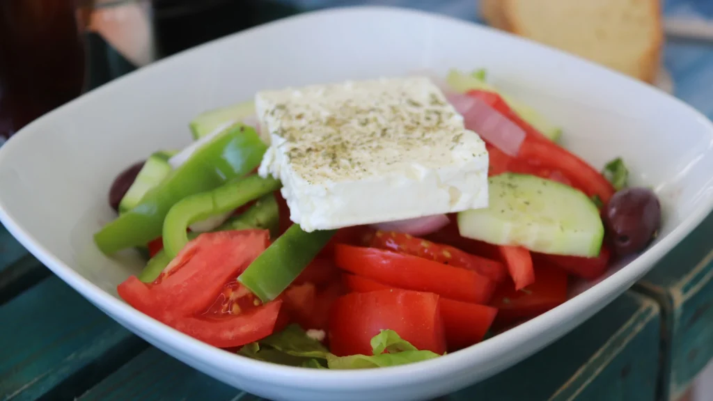 Greek salad with a slab of feta, tomato, cucumber and green pepper, ready for a Greek salad dressing recipe