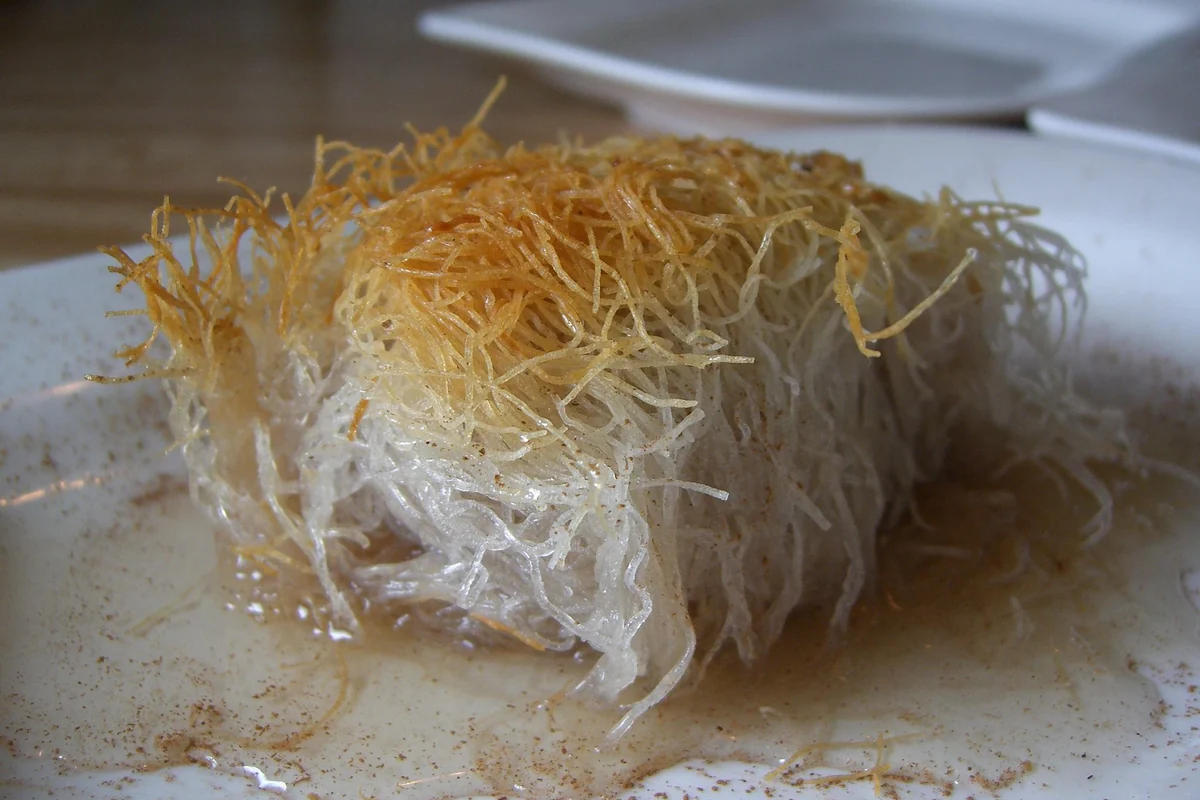 A roll of kataifi, shredded pastry wrapped around nuts and soaked in syrup