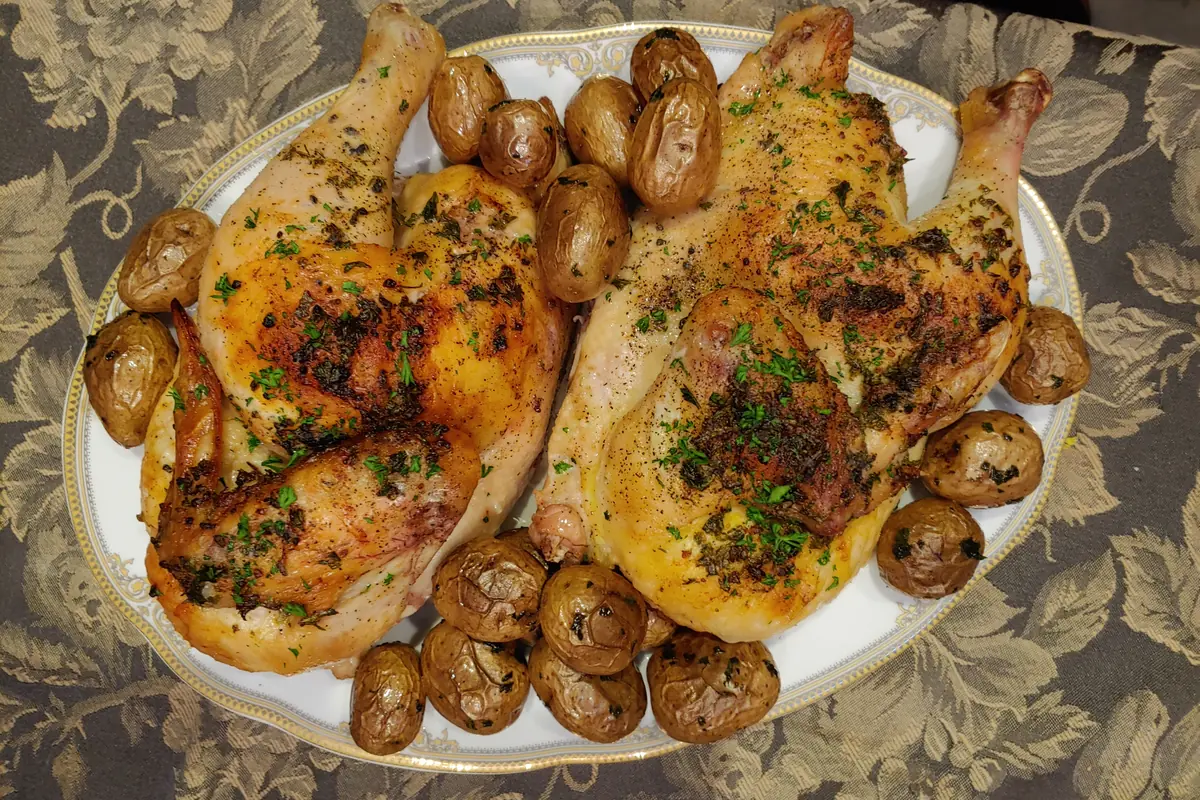 Two halves of chicken roasted with garlic, lemon and herbs, with potatoes