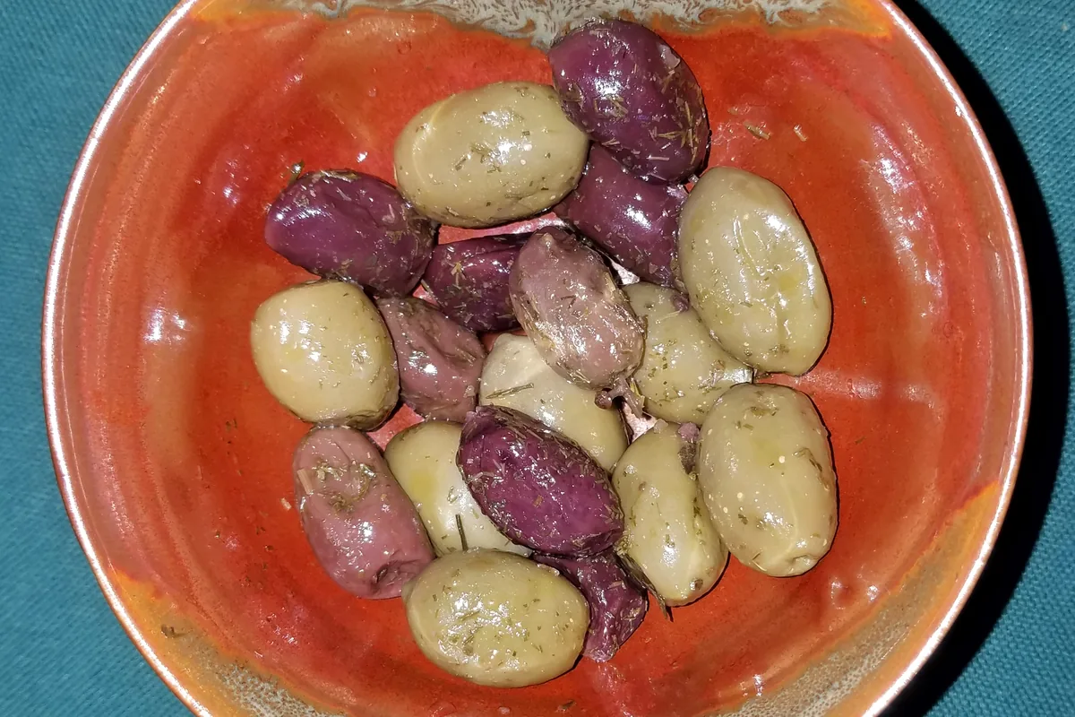 Marinated mixed olives, green and purple, in a red bowl