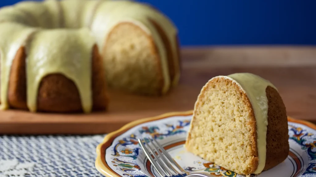 Glazed olive oil and semolina bundt cake with a slice cut and served on a plate