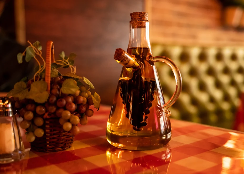 Glass oil cruet on a table, illustrative ingredient reference