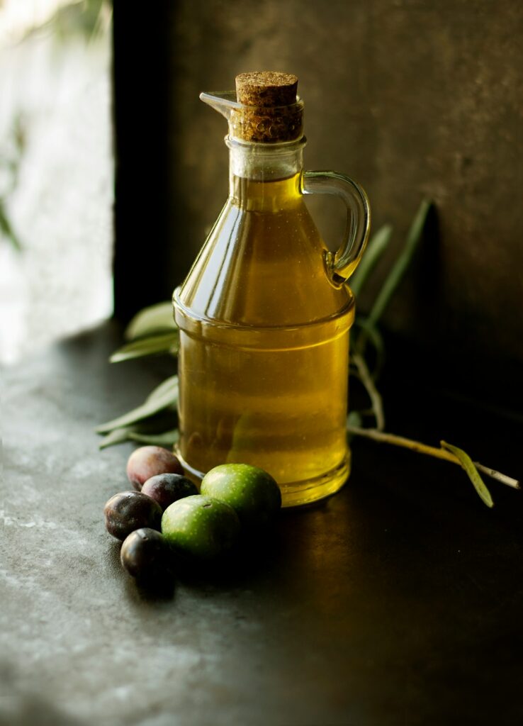Glass jug of olive oil with olives