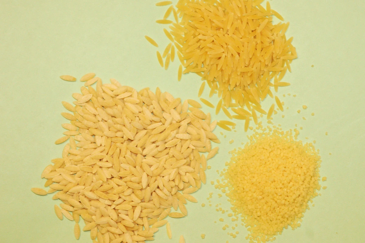 Dry orzo pasta beside risi and couscous, showing orzo’s rice-like shape