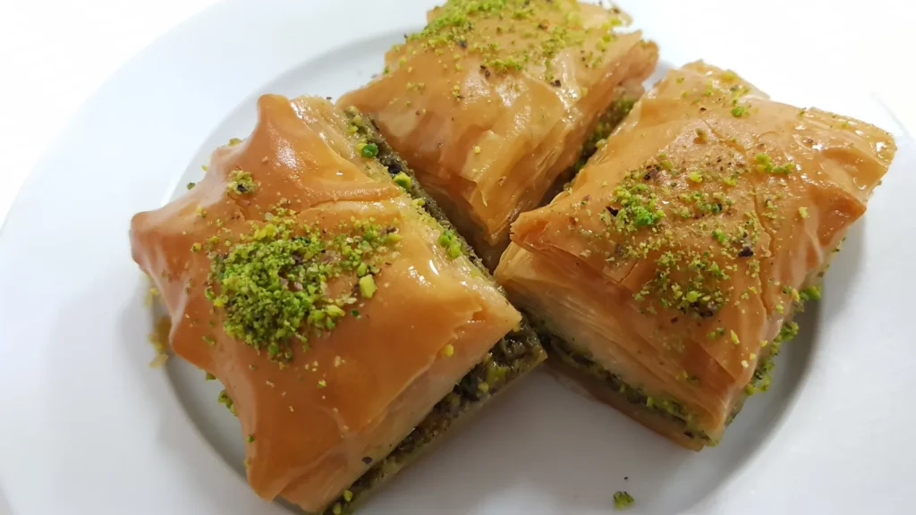 Pieces of crisp baklava topped with chopped pistachios on a plate