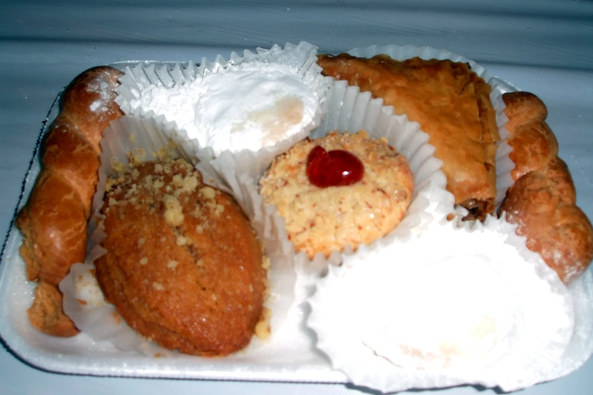 A mixed plate of Greek holiday cookies and pastries, with a powdered-sugar kourabies on the right