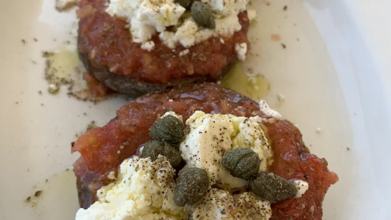 A plate of Cretan dakos: barley rusks topped with grated tomato, white cheese, capers and oregano