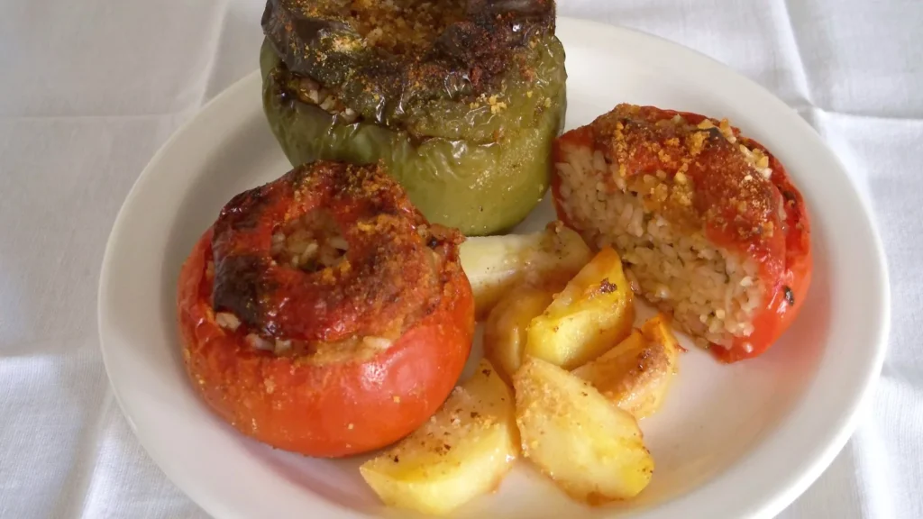 A plate of gemista, Greek stuffed tomatoes and peppers, with roasted potato wedges