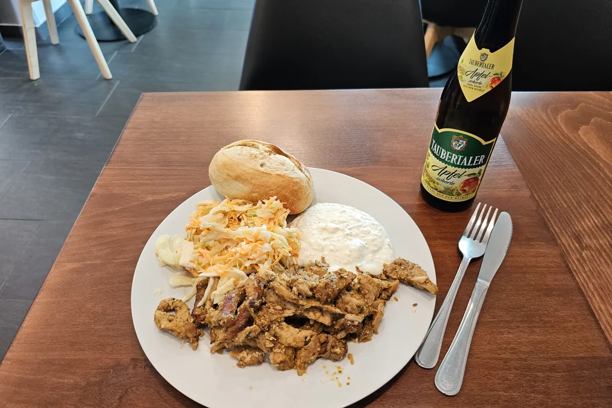 A plate of sliced gyros meat with chips, salad and tzatziki