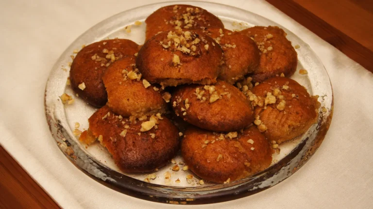 A plate of Greek melomakarona, honey-soaked Christmas cookies topped with chopped walnuts