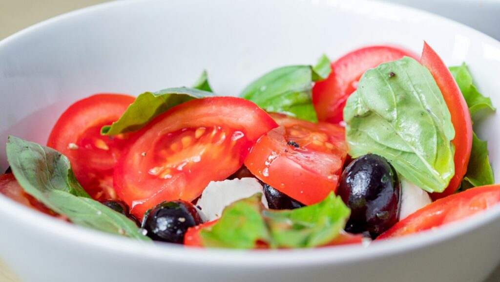 Tomato, dark olives, mozzarella and basil in a salad