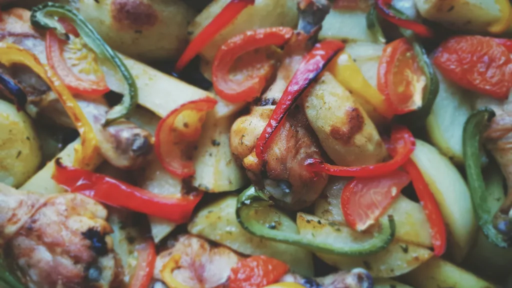 A baking tray of roasted mixed vegetables, including peppers, courgettes and red onion