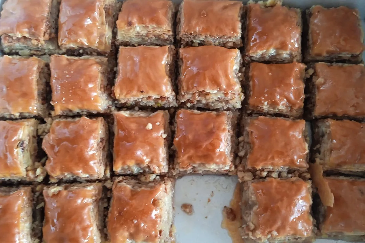 A tray of walnut baklava cut into squares and soaked in syrup