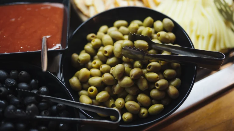 Trays of green olives and black olives side by side at a food display
