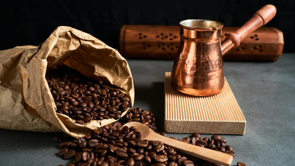 Copper briki coffee pot beside a sack of coffee beans, the traditional Greek coffee pot