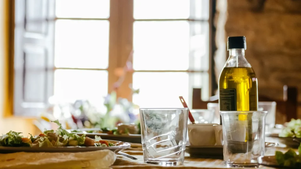 Bottle of olive oil on a sunny family lunch table, the everyday setting for choosing Greek olive oil