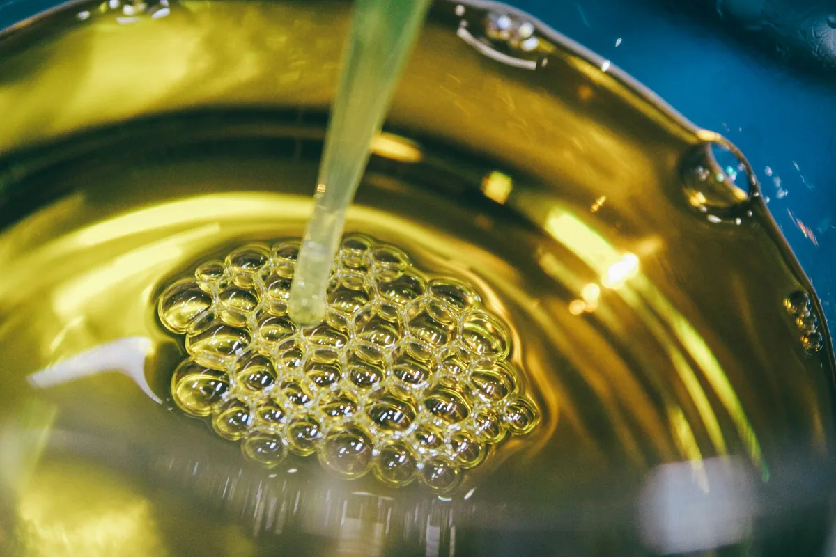 Close-up of golden extra virgin olive oil pouring into a bowl