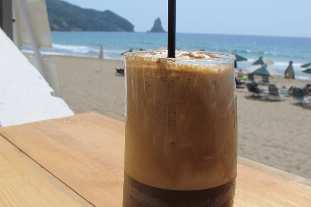 Glass of foamy Greek frappe with a straw, the classic frappe recipe result
