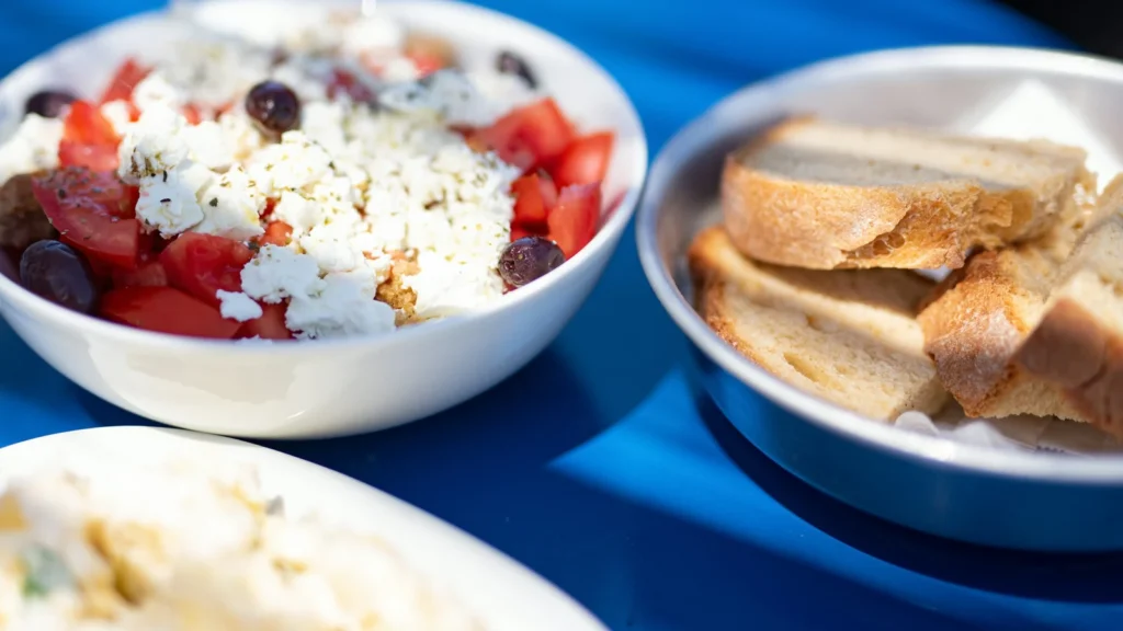 Greek pantry mezze table with salad, bread and dips on a blue cloth