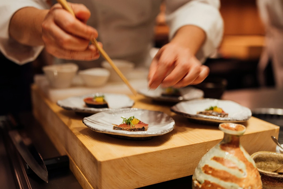 Chef plating small dishes in a restaurant kitchen, where Greek products for restaurants are used