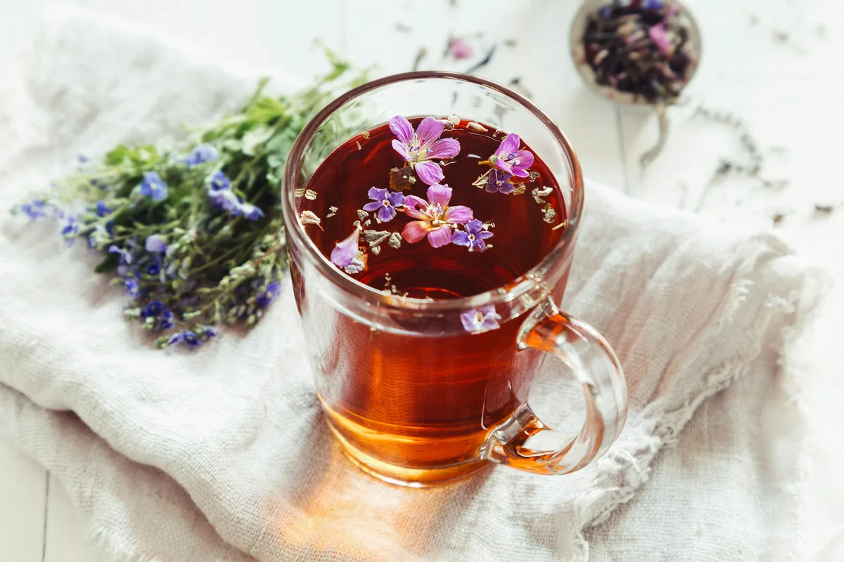 Cup of herbal tea with dried blossoms on a linen cloth