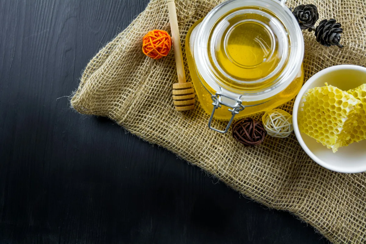 Jar of honey with honeycomb and a dipper, a favourite for a Greek food gift basket