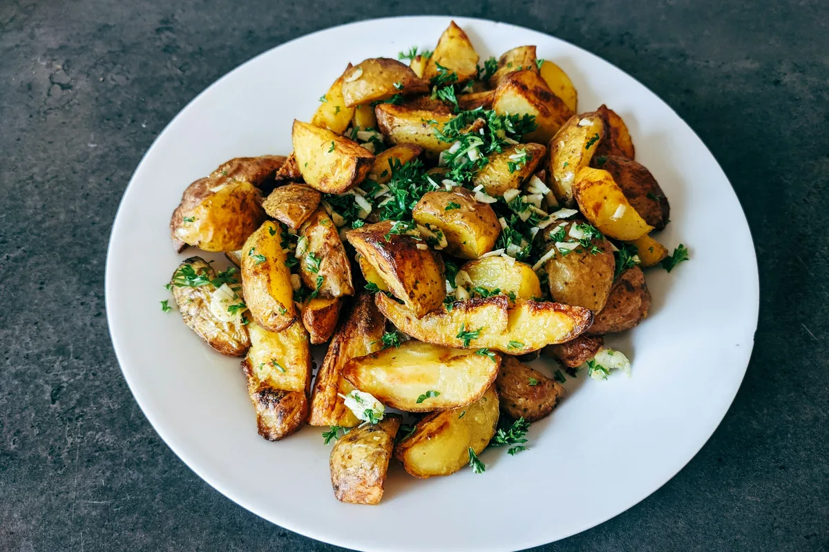 Roast potatoes with herbs on a white plate, a classic dish for Greek oregano