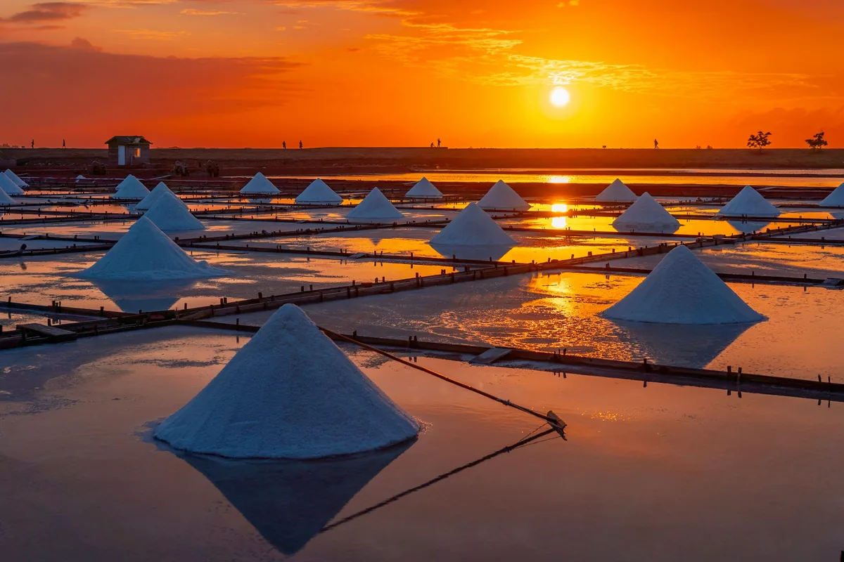 Sea salt pans at sunset with harvested salt piles, where fleur de sel vs Maldon differences begin